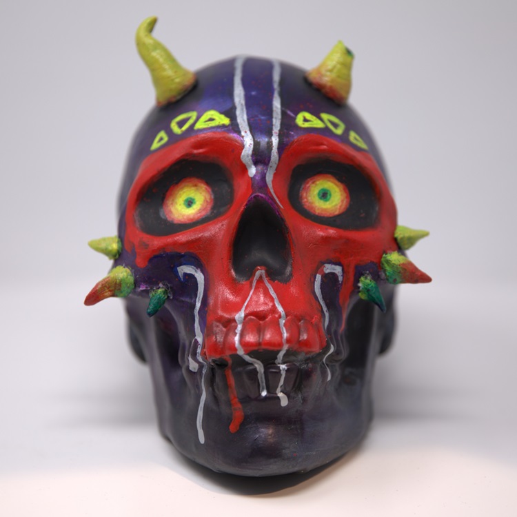 Black, red, and purple painted skull with neon details, spikes near the cheeks and horns.