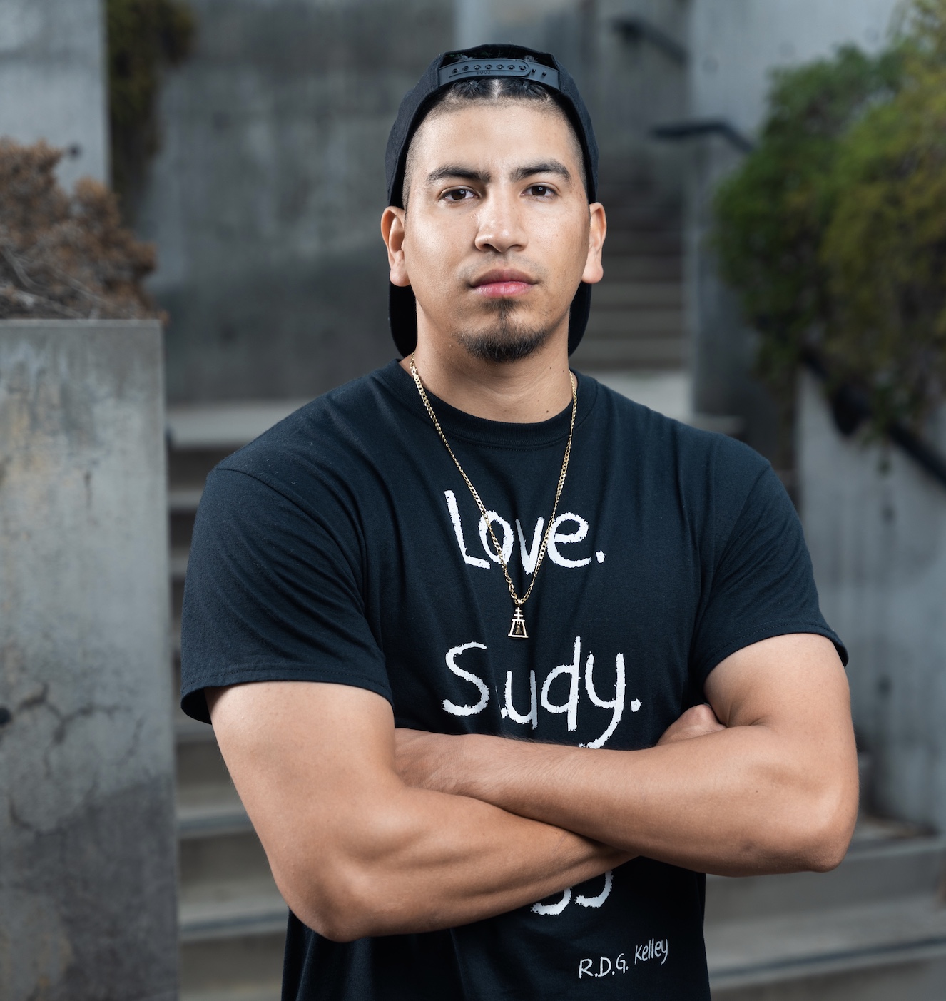 Humerto Flores, arms crossed, black t-shirt reading "Love, Study"
