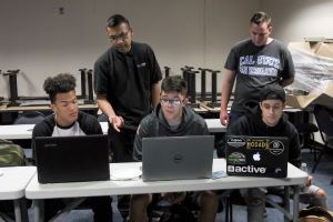 Technology Support Center staff assisting students on laptop computers.