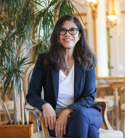 Jane Chind Davidson, seated, white shirt, bue suit, glasses