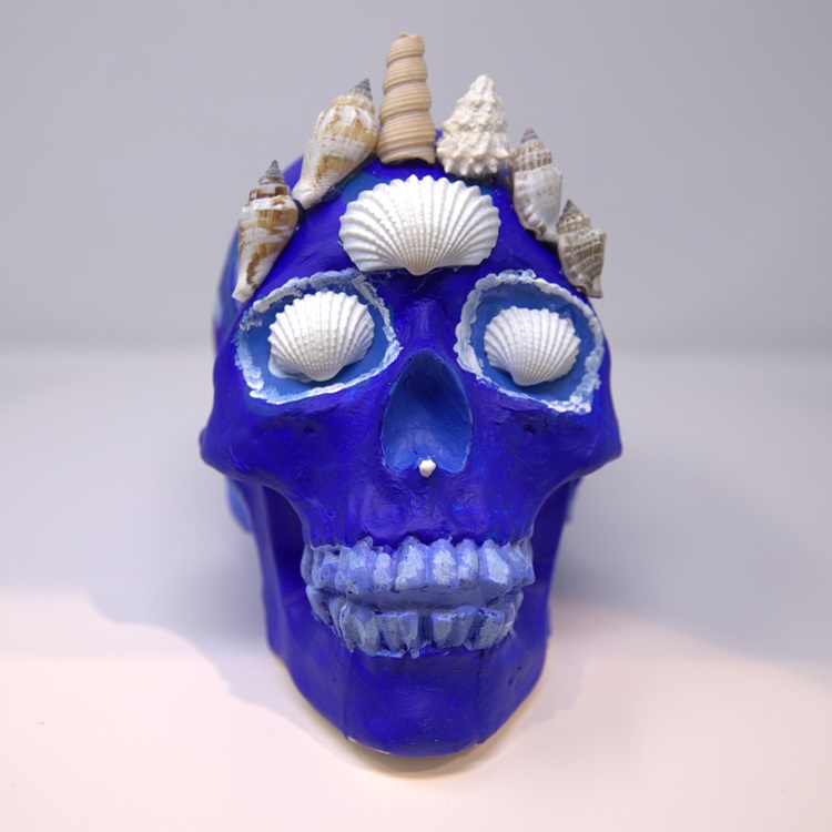 Blue painted skull with white detailing, shell inset eyes and a crown of shells.