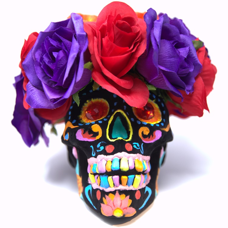 Black painted skull decorated in a sugar skull style with red gemstone eyes, and a crown of roses.