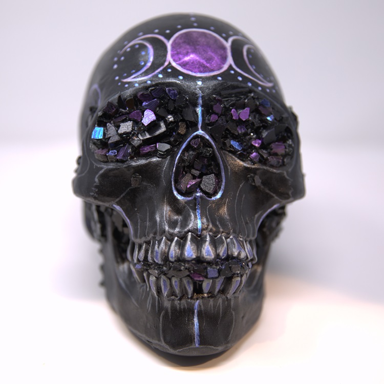 Black painted skull with metallic details in blue and purple featuring gem formations for the eyes & nose.