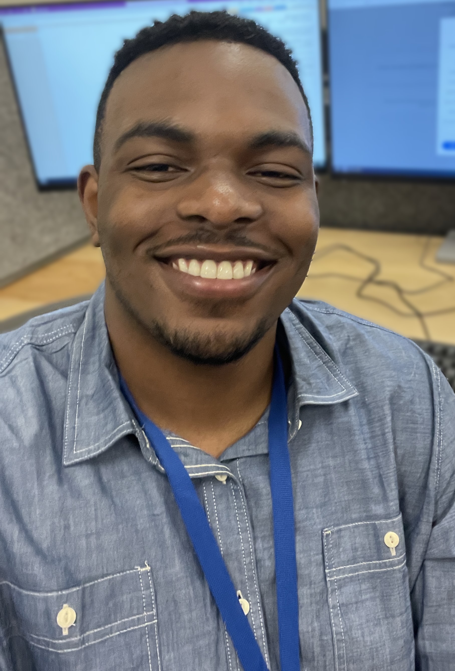 brown eyes and black short hair, blue polo shirt, smiling