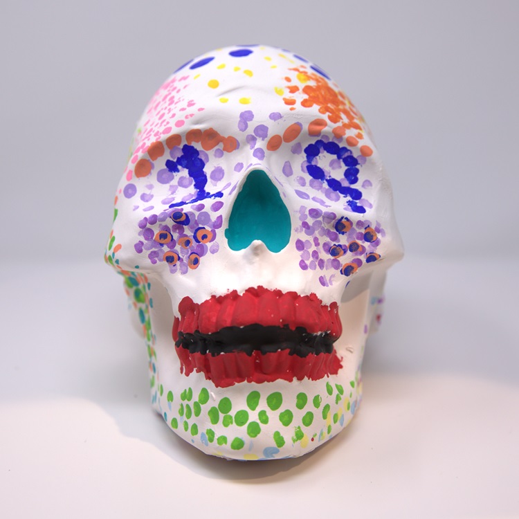 White skull with dot pattern decorations in blue, pink, orange, red, green and yellow, and dot patterns in the eye forming the number 19