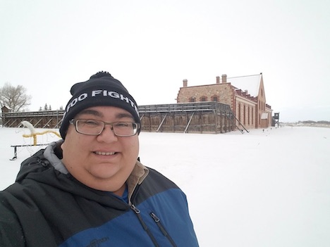 Slider stands in the snow in front of background building