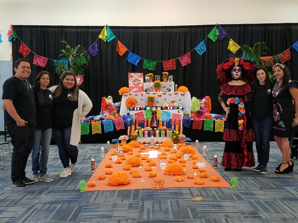 Club members, Advisor and a student dressed as la Catrina stand by the alter they created