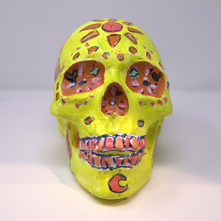 Yellow painted skull with decorations in orange and red.