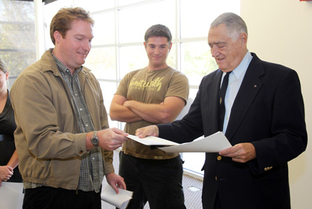 Three people standing two trading papers