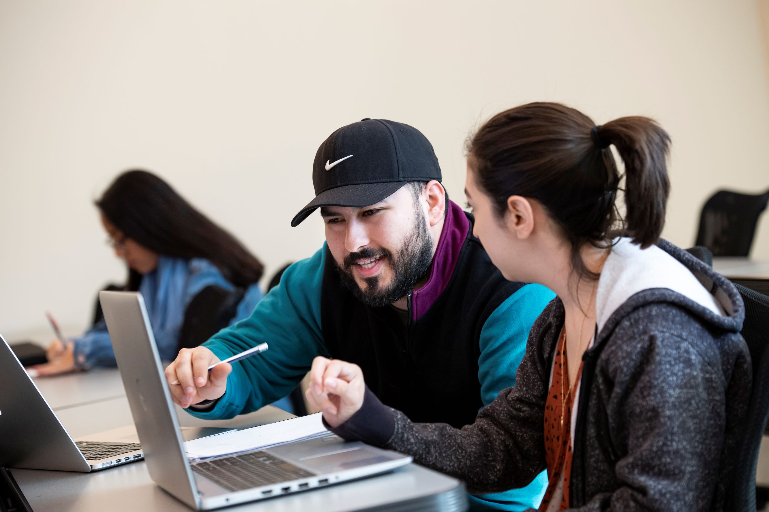 Two students working at laptop