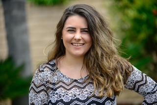 Hannah Knight, brown hair, gray sweater, smiles at the camera