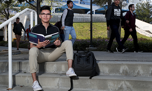 Student sitting on steps with book